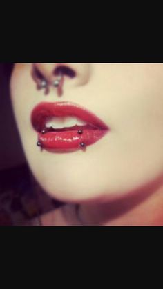 a woman with red lipstick and piercings on her face