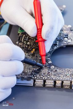 a person in white gloves is working on a motherboard with a red plastic marker