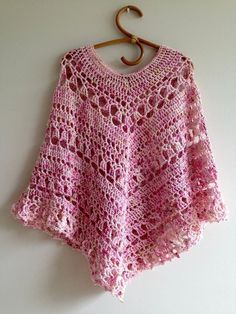 a pink crocheted sweater hanging on a hook