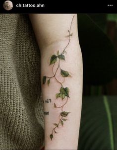 a woman's arm with green leaves on it