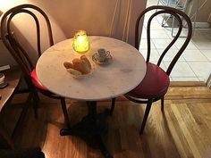 a cat sitting on the floor next to a table with two chairs and a candle