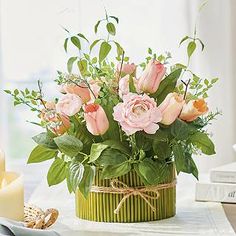 a vase filled with pink flowers sitting on top of a table next to a candle