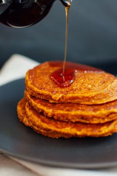 a stack of pancakes with syrup being poured on top