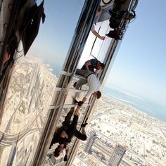 two men climbing up the side of a tall building with their feet in the air