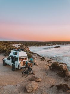 an rv parked on the beach with its doors open and two bicycles leaning against it