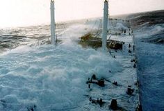 a large body of water with waves crashing over it and people standing on the dock