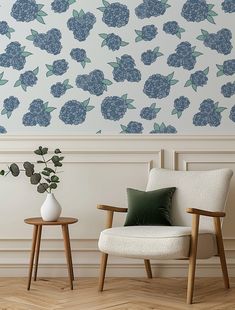 two wooden chairs sitting next to each other in front of a wall with blue flowers on it