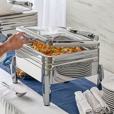 a buffet table with plates and silverware on it, including a serving tray filled with food