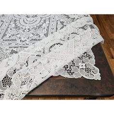 an image of a white lace tablecloth on a wooden table with wood flooring