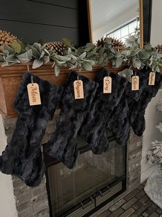 stockings hanging from a mantel decorated with greenery and pine cones, along with tags that say happy new year