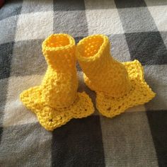 two crocheted yellow boots sitting on top of a checkered tablecloth covered floor