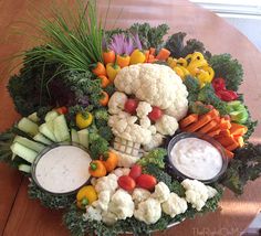 an arrangement of vegetables and dips on a wooden table