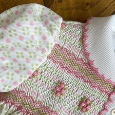 a knitted sweater with pink and green flowers on it sitting on a wooden floor