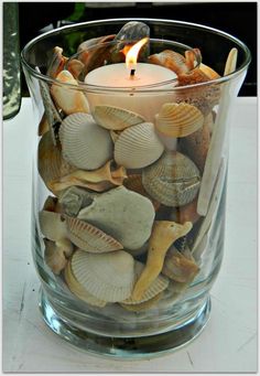 a glass vase filled with rocks and a lit candle