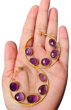 Beautiful, hand crafted statement hoops with faceted amethyst gemstones in a regal purple hue. 14k gold plated nickel free brass genuine amethyst gemstones dimension: approx. 1.75" handcrafted by artisans Luxury Oval Gemstone Hoop Earrings, Purple Gemstone Hoop Earrings, Purple Amethyst Hoop Jewelry, Adjustable Purple Hoop Earrings, Adjustable Purple Round Hoop Earrings, Purple Hoop Jewelry, Purple Amethyst Hoop Earrings For Gift, Purple Brass Jewelry With Matching Earrings, Nickel-free Purple Hoop Earrings