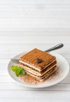 a stack of layered cake sitting on top of a white plate next to a fork