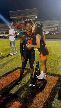 two people standing on a football field hugging each other