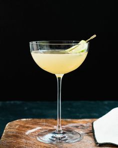 a glass filled with a drink sitting on top of a wooden cutting board