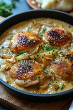 a pan filled with chicken and onions covered in gravy on top of a wooden cutting board