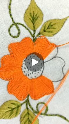 an orange flower with green leaves is embroidered onto a white fabric material that has been stitched together