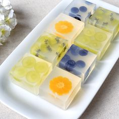 four squares of soap sitting on top of a white platter next to a flower