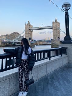 a woman standing on the side of a bridge