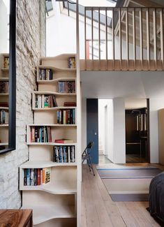 there is a book shelf with books on it in the living room next to stairs