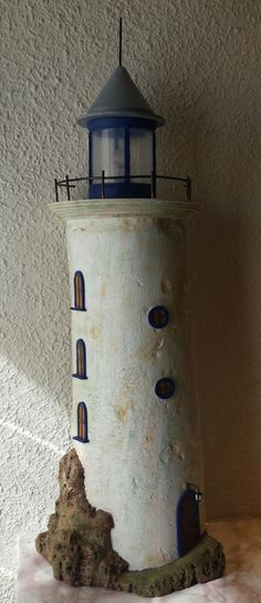 a white and blue light house on top of a wooden table next to a wall