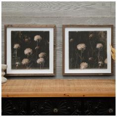 two framed pictures sitting on top of a wooden table