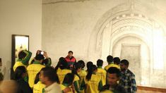 a group of people in yellow and green shirts standing next to each other near a wall