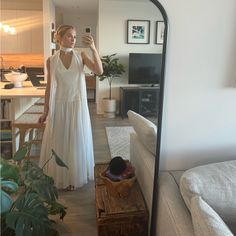 a woman in a white dress taking a selfie with her cell phone while standing in front of a mirror