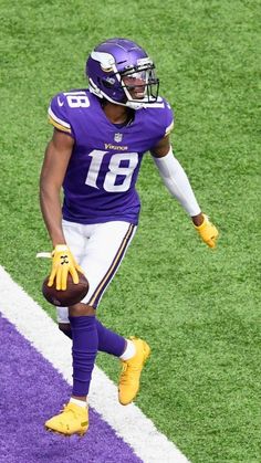 a football player running on the field with a ball in his hand and yellow gloves