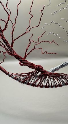 a wire sculpture is shown in the middle of a white background with red and silver lines on it