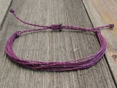 a purple string bracelet sitting on top of a wooden floor