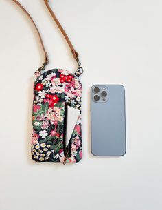 a cell phone case sitting on top of a white table next to a flowered purse