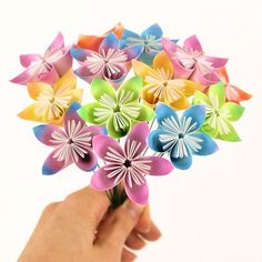 a hand holding a bunch of colorful paper flowers