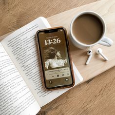 an iphone sitting on top of a book next to a cup of coffee