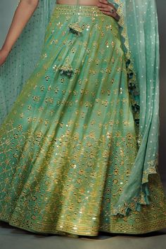 Sea green lehenga in raw silk embroidered with dull yellow resham work and mirror work. Paired with a co-ordinating blouse and organza dupatta with zari dots.
Component: 3
Embroidered
Neckline: V-Neck
Sleeve Length: Half
Fabric: 100 grams Pure Raw Silk,  Organza
Color: Green
Plunge V-neck blouse
Back V-neck blouse with tassel tie-up
Resham and mirror work embroidery all-over
Zig-zag cutwork dupatta hem
Closure:
Blouse: Front hook closure and tassel tie-up
Lehenga: Side zip closure with tassel ti Semi-stitched Tussar Silk Choli With Dori Work, Green Embroidered Saree For Reception, Designer Resham Embroidery Raw Silk Lehenga, Designer Resham Embroidered Raw Silk Lehenga, Designer Raw Silk Lehenga With Resham Embroidery, Green Resham Embroidery Choli For Reception, Green Semi-stitched Lehenga With Dupatta, Green Choli With Resham Embroidery For Reception, Semi-stitched Green Lehenga With Dupatta