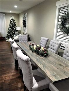 a dining room table with white chairs and christmas decorations on the top, along with greenery