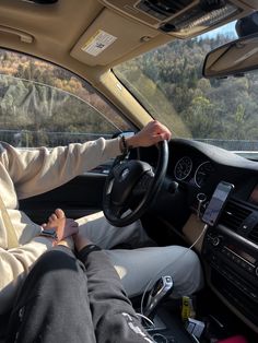 a person sitting in the driver's seat of a car with their hands on the steering wheel