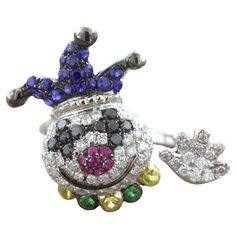 A fun and friendly clown studded in diamonds and colored gemstones. The smiling clown features 0.90 carats of white and black diamonds making its face, eyes, and hand along with 0.48 carats of rubies and sapphires which make its hat and nose. It has a collar of green and yellow gemstones to finish his outfit. Made in 18k white gold and ready to be worn! Ring Size 7.75 Weight: 6.4 grams Colored Gemstones, Yellow Gemstones, Gemstone Colors, Black Diamond, Fashion Rings, Ruby, White And Black, Jewelry Rings, Sapphire