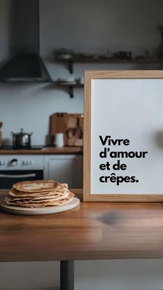 a wooden table topped with stacks of pancakes next to a framed sign that says vivre d'amour et de crepes