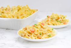 two white bowls filled with pasta and vegetables