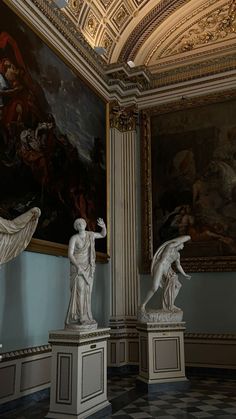 two statues in a room with paintings on the walls