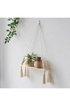 some plants are hanging on a shelf with tassels