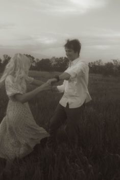 a man and woman are dancing in the middle of an open field with tall grass