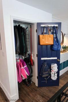 an open closet with several coats and purses hanging on hooks, in a house