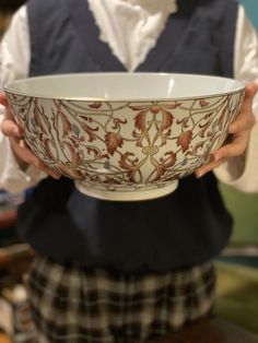 a person holding a bowl in their hands with an ornate design on the bottom and sides