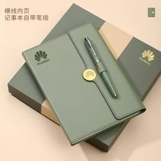 a notebook with a pen sitting on top of it next to two folders that are both green