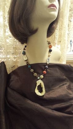 "One strand beaded faceted necklace with center drop. The drop measures 2 1/2\" long and about 1 1/2\" wide. The necklace measures 20\" long. Some of the variety of stones used in this necklace is jasper, onyx, shell coral. The drop is the inside of a druzy. Looks great with lots of outfits. If you like it \" pin it \" or share on Facebook." Adjustable Dangle Necklaces With Large Beads, Costume Jewelry Beaded Necklaces With Faceted Beads, Costume Jewelry Beaded Necklace With Faceted Beads, Unique Long Beaded Necklace With Faceted Beads, Adjustable Beaded Teardrop Necklace, Artisan Beaded Pendant Necklace With Faceted Beads, Artisan Beaded Teardrop Necklaces, Artisan Beaded Necklace With Faceted Pendant, Artisan Pendant Beaded Necklace With Faceted Beads